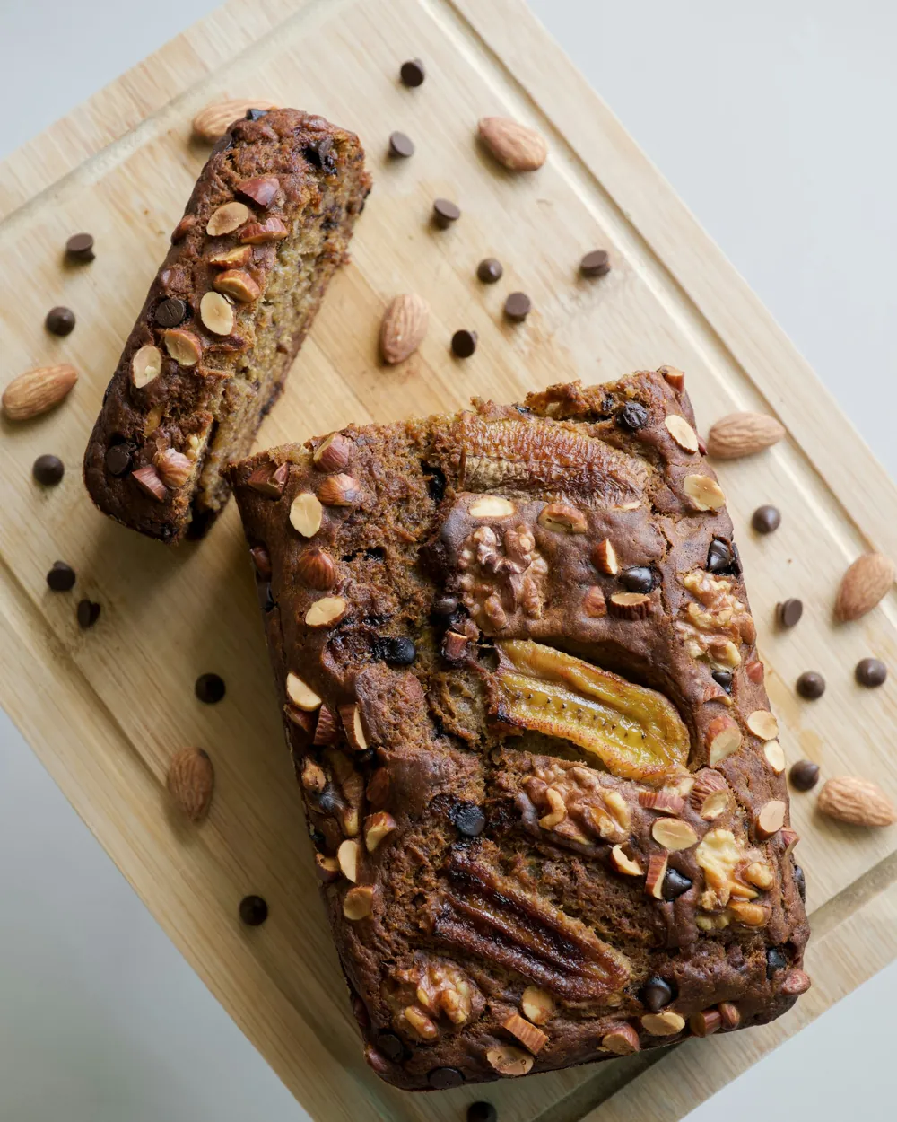 Banana bread aux noix, amandes et bananes caramélisées sur une planche en bois
